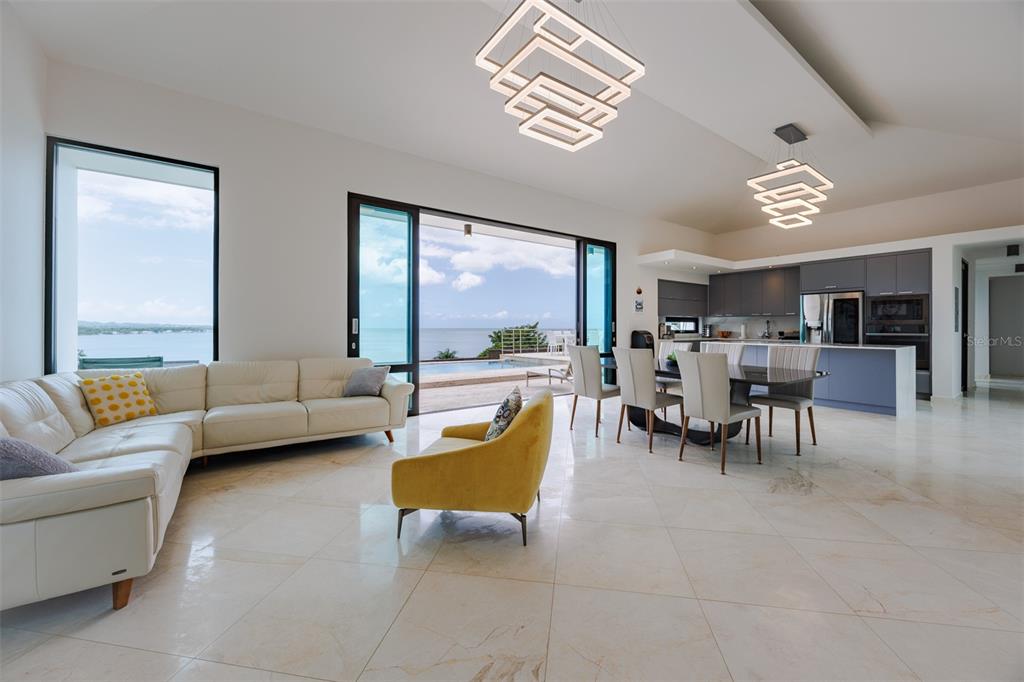 A modern open-concept living and dining area features white tile floors, contemporary lighting, and ocean views — 6 PARAISO ESCONDIDO, CABO ROJO, PR