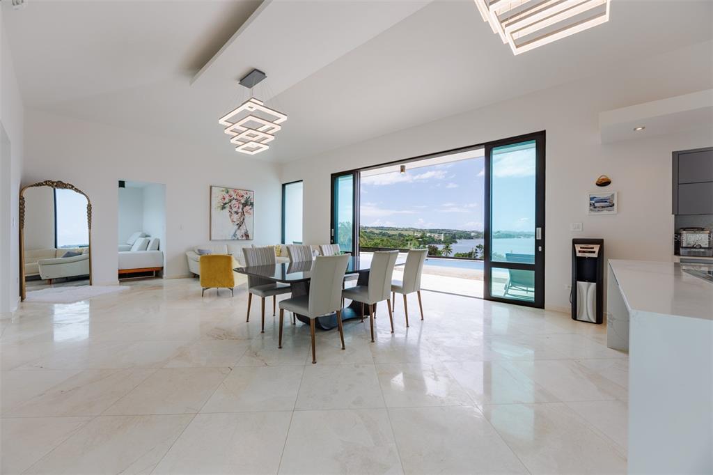 A bright, open-concept dining and living area features marble floors, modern lighting, and sliding glass doors — 6 PARAISO ESCONDIDO, CABO ROJO, PR