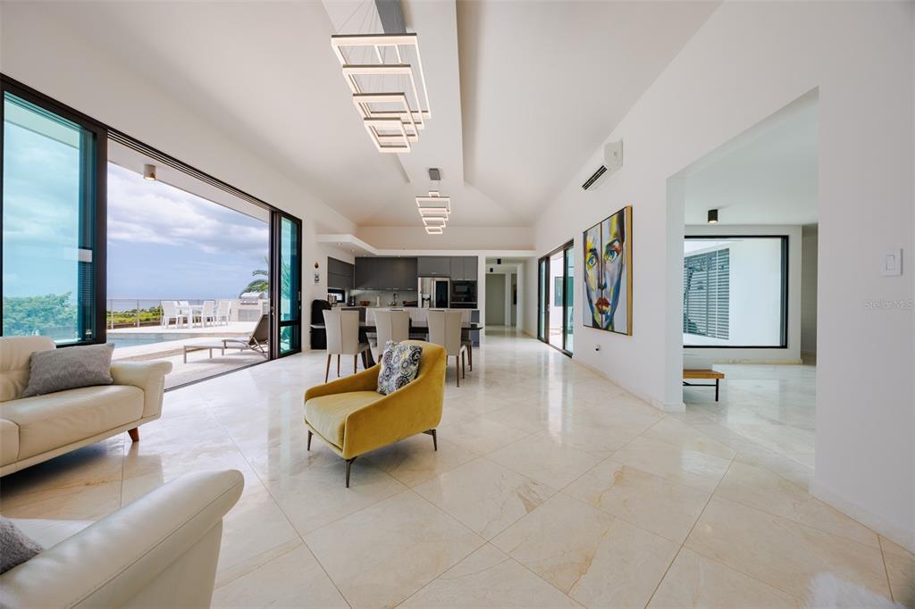 A modern open-concept living and dining area features marble floors, contemporary lighting, and sliding doors — 6 PARAISO ESCONDIDO, CABO ROJO, PR