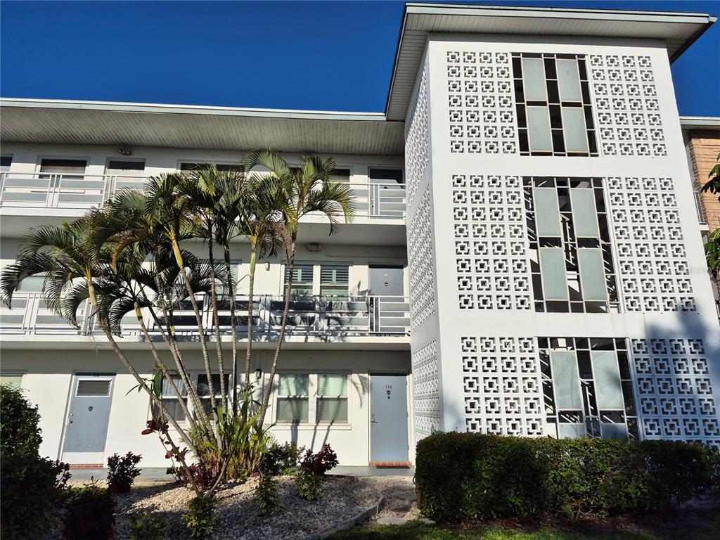 A three-story apartment building features white exterior walls, open walkways, and decorative concrete breeze blocks — 6000 20TH STREET N UNIT 116, ST PETERSBURG, FL