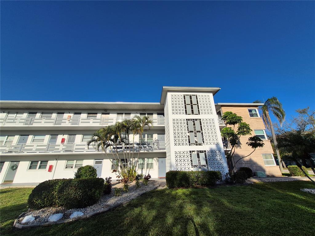 A three-story apartment building with a white facade, exterior walkways, and decorative concrete block screens — 6000 20TH STREET N UNIT 116, ST PETERSBURG, FL