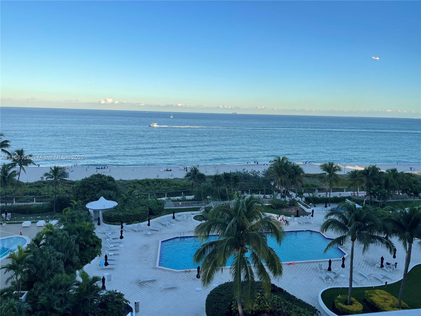 An elevated view of a swimming pool, palm trees, sandy beach, and the ocean — 5161 Collins Ave # 914, Miami Beach FL 33140, MIAMI BEACH, FL
