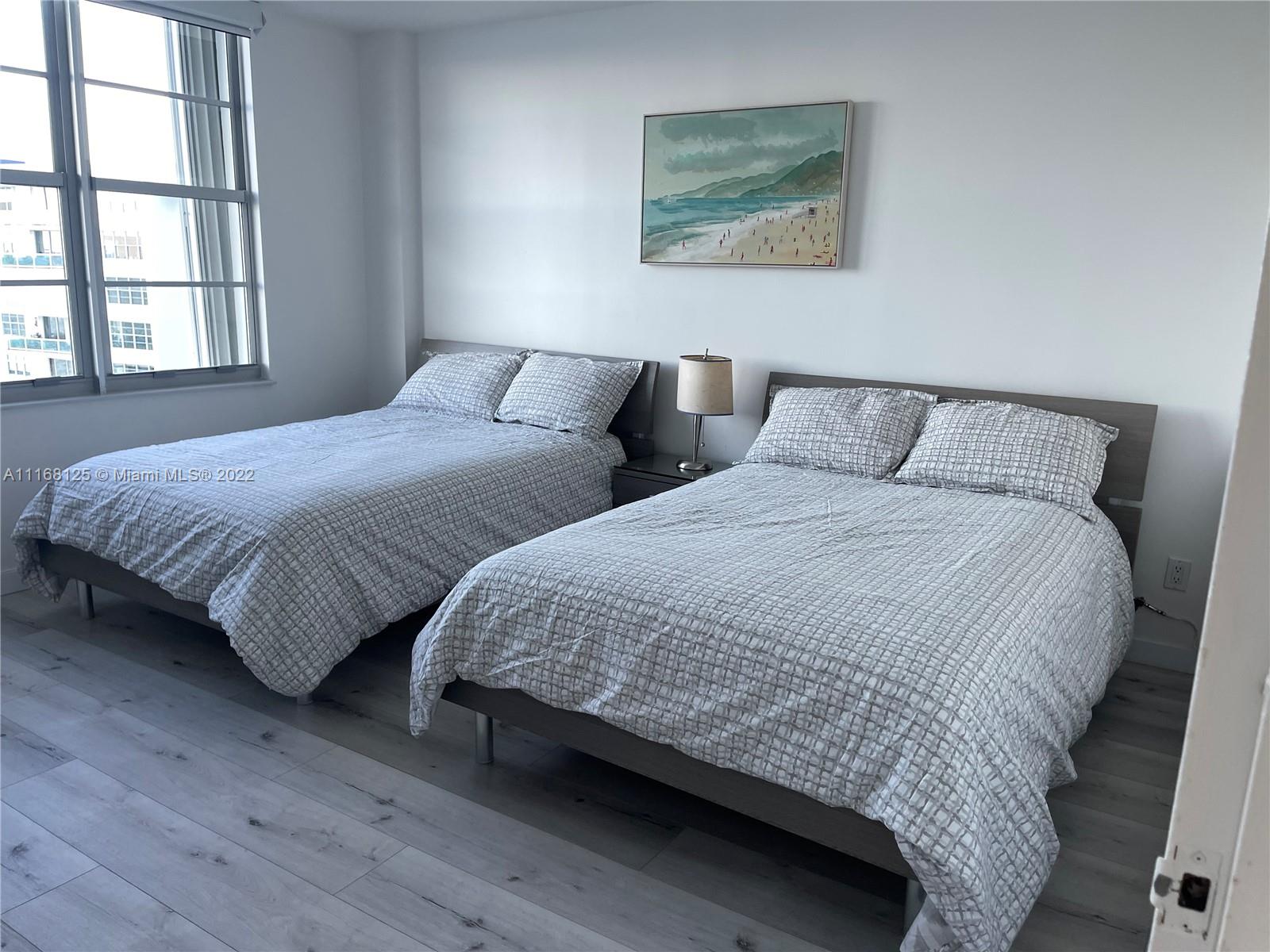A bedroom features two beds with gray patterned bedding, a nightstand, and a beach painting — 5161 Collins Ave # 914, Miami Beach FL 33140, MIAMI BEACH, FL