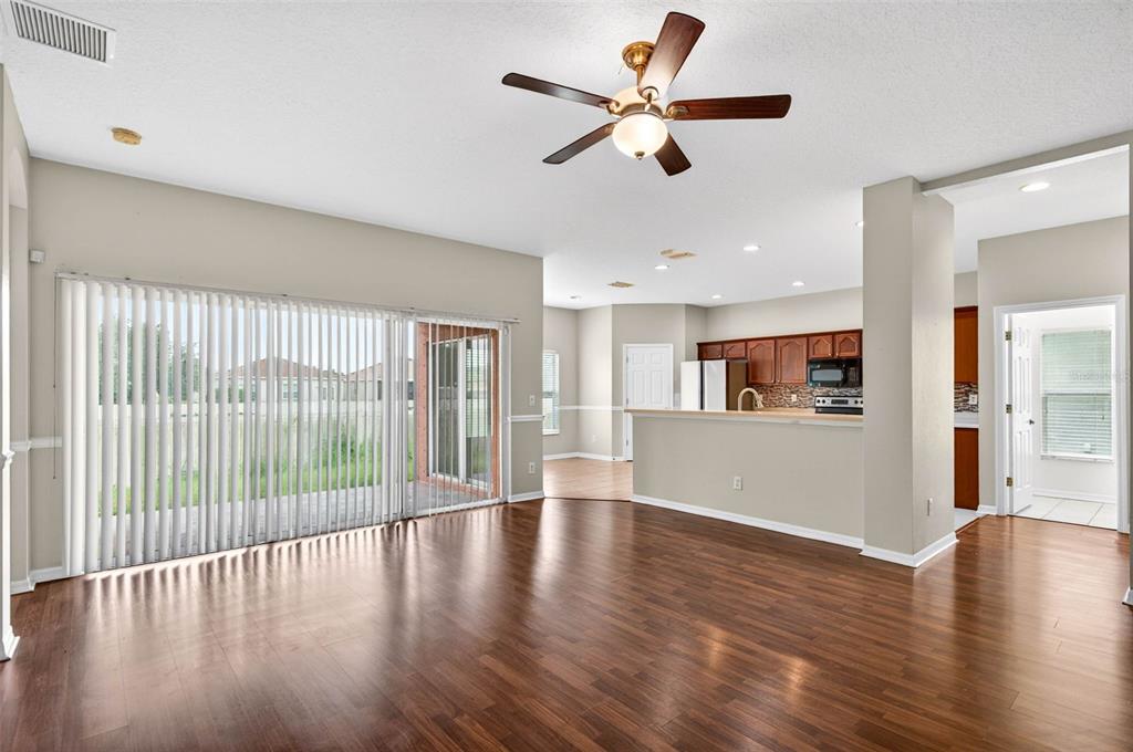 An open-concept living area with wood flooring, a ceiling fan, and a kitchen with cabinets — 612 MARION HILL LANE, RUSKIN, FL