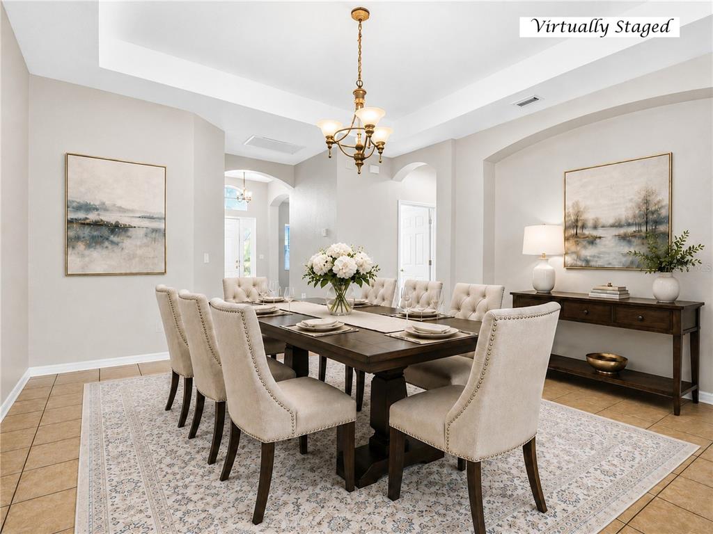 A dining room features a dark wood table, upholstered chairs, and a chandelier on tile flooring — 612 MARION HILL LANE, RUSKIN, FL