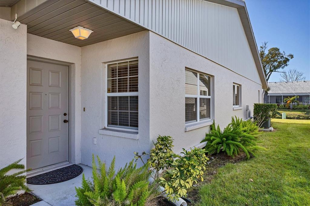 The exterior of a house features a gray front door, windows, and a landscaped yard — 5478 KELLY DRIVE UNIT 7, SARASOTA, FL