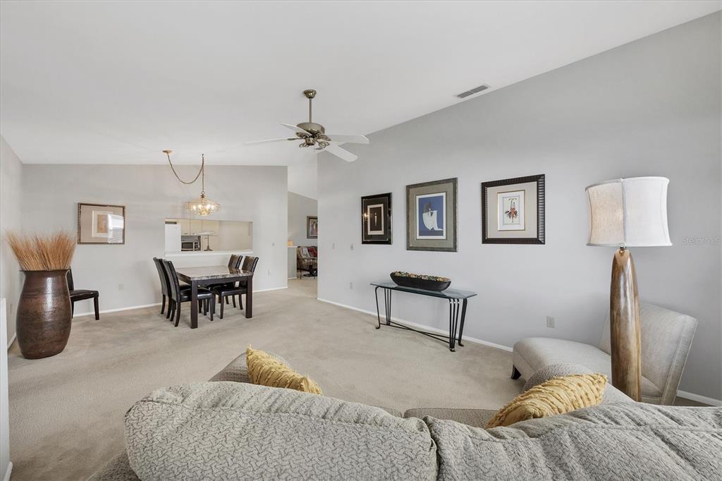 A living room and dining area with neutral carpet, light walls, and a ceiling fan — 5478 KELLY DRIVE UNIT 7, SARASOTA, FL