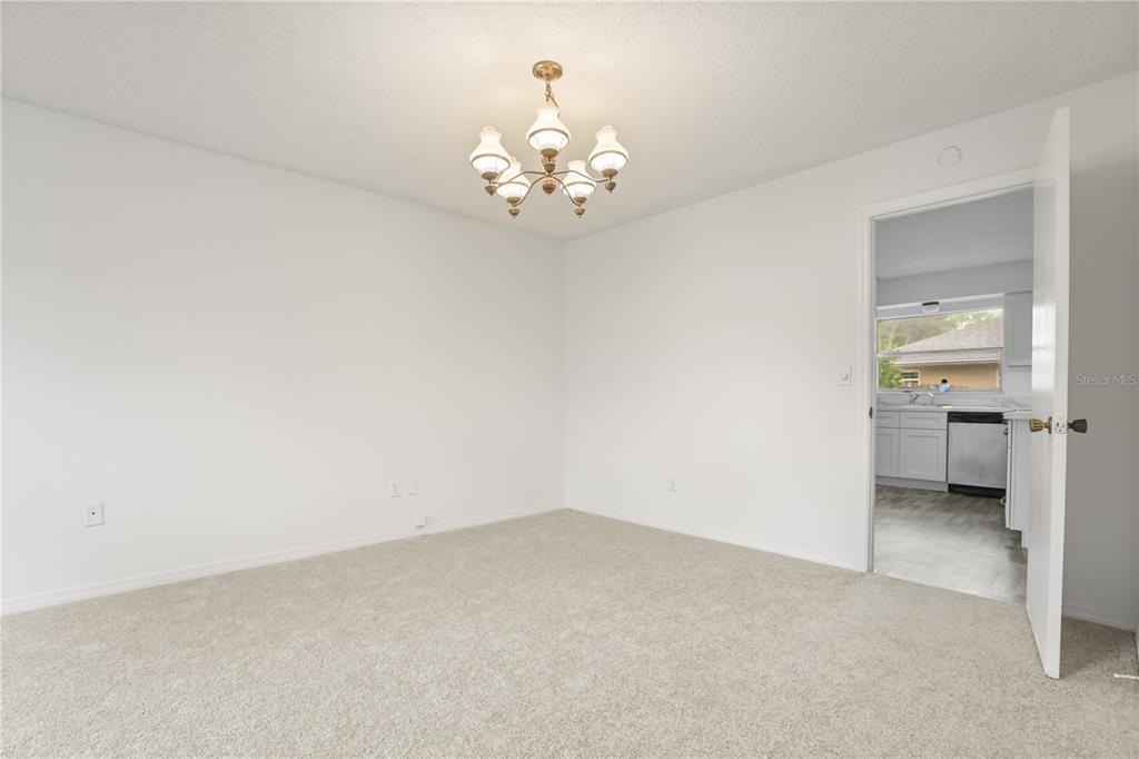 A carpeted dining room with a chandelier leads into a kitchen through an open doorway — 5310 NADINE STREET, ORLANDO, FL