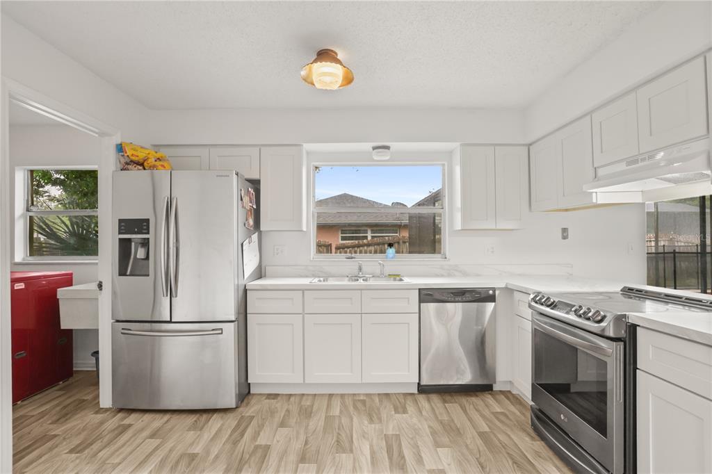 A kitchen with white cabinets, stainless steel appliances, and wood-look flooring — 5310 NADINE STREET, ORLANDO, FL