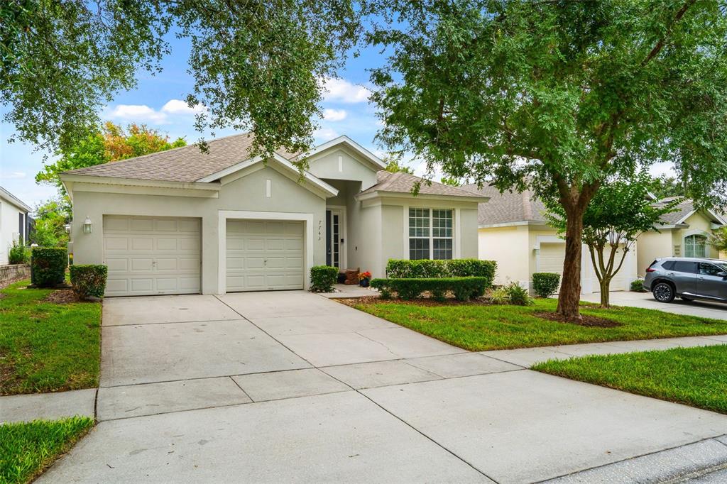 A single-story suburban house with a two-car garage, concrete driveway, and manicured landscaping — 7743 COMROW STREET, KISSIMMEE, FL
