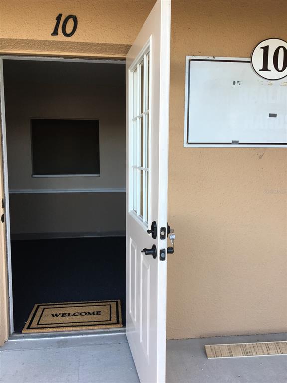 An open white door leads into a small office space with a welcome mat — 13910 FIVAY ROAD UNIT 10, HUDSON, FL