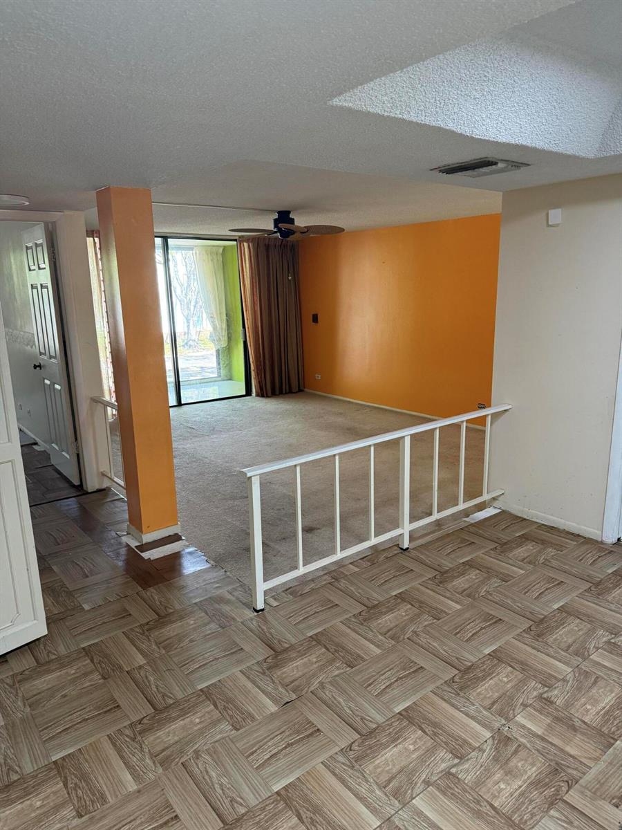 A living room features orange walls, a white railing, and wood-look flooring — 3730 Inverrary Drive # 2a, Lauderhill FL 33319, LAUDERHILL, FL
