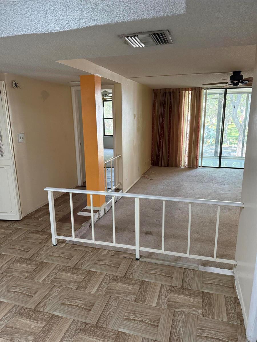A split-level living area features wood-look flooring, a white railing, and a bright orange pillar — 3730 Inverrary Drive # 2a, Lauderhill FL 33319, LAUDERHILL, FL