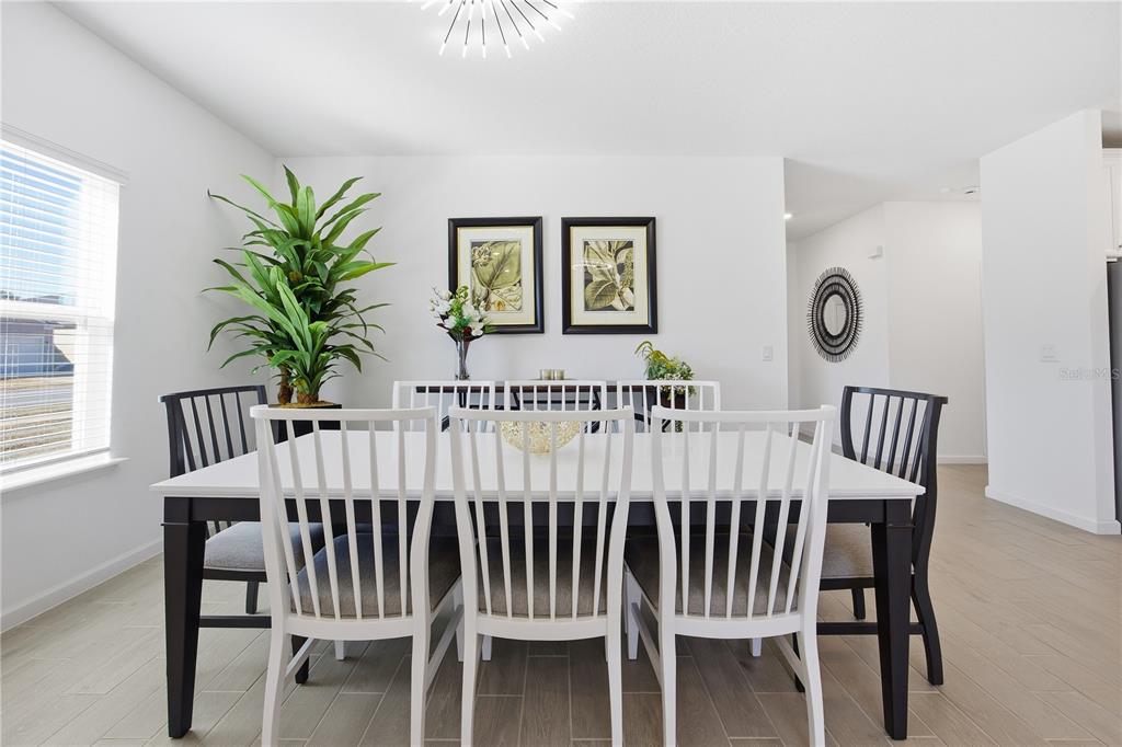 A dining room features a white table with black-and-white chairs, a plant, and wall art — 7561 SW 76TH TERRACE, OCALA, FL