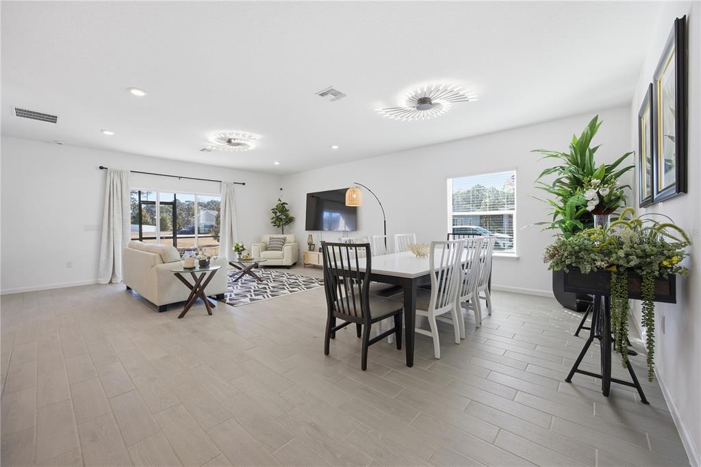 A bright, open-concept living and dining area features white walls, tile flooring, and modern lighting — 7561 SW 76TH TERRACE, OCALA, FL