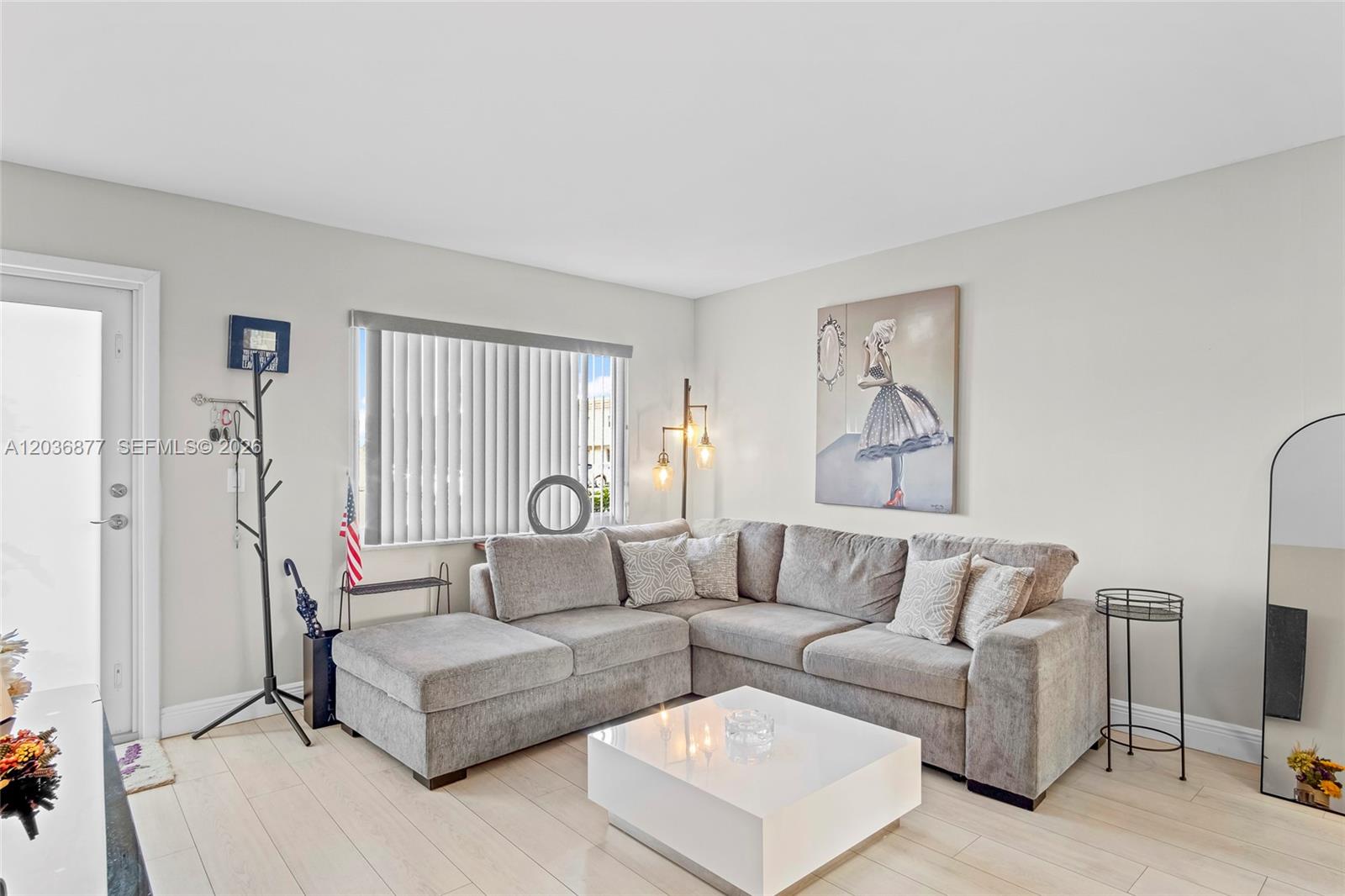 A living room features a gray sectional sofa, a white coffee table, and light flooring — 19 Abbey Ln # 104, Delray Beach FL 33446, DELRAY BEACH, FL