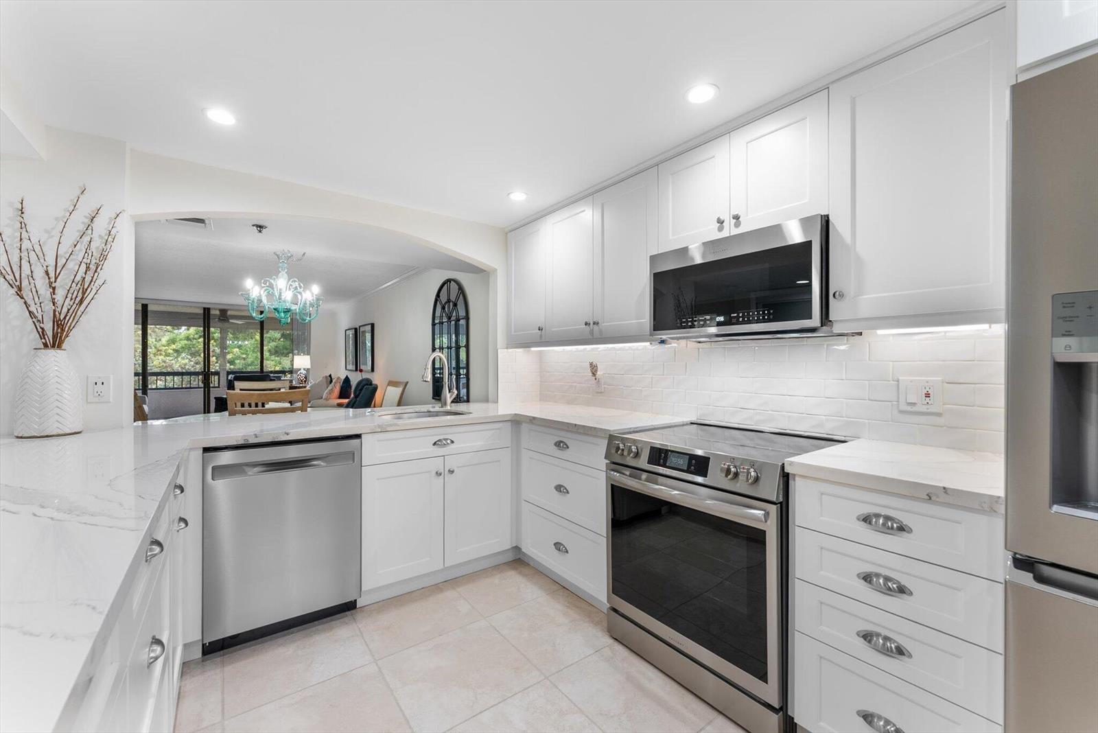 A modern kitchen features white cabinetry, stainless steel appliances, and white marble-style countertops — 6420 Boca Del Mar Drive # 201, Boca Raton FL 33433, BOCA RATON, FL