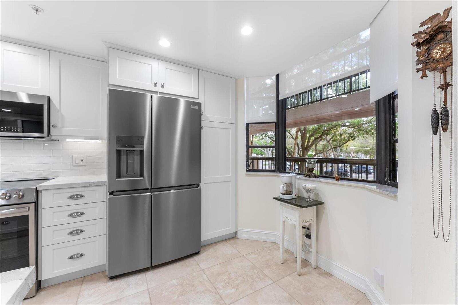 A kitchen features white cabinets, stainless steel appliances, tile flooring, and a windowed breakfast nook — 6420 Boca Del Mar Drive # 201, Boca Raton FL 33433, BOCA RATON, FL