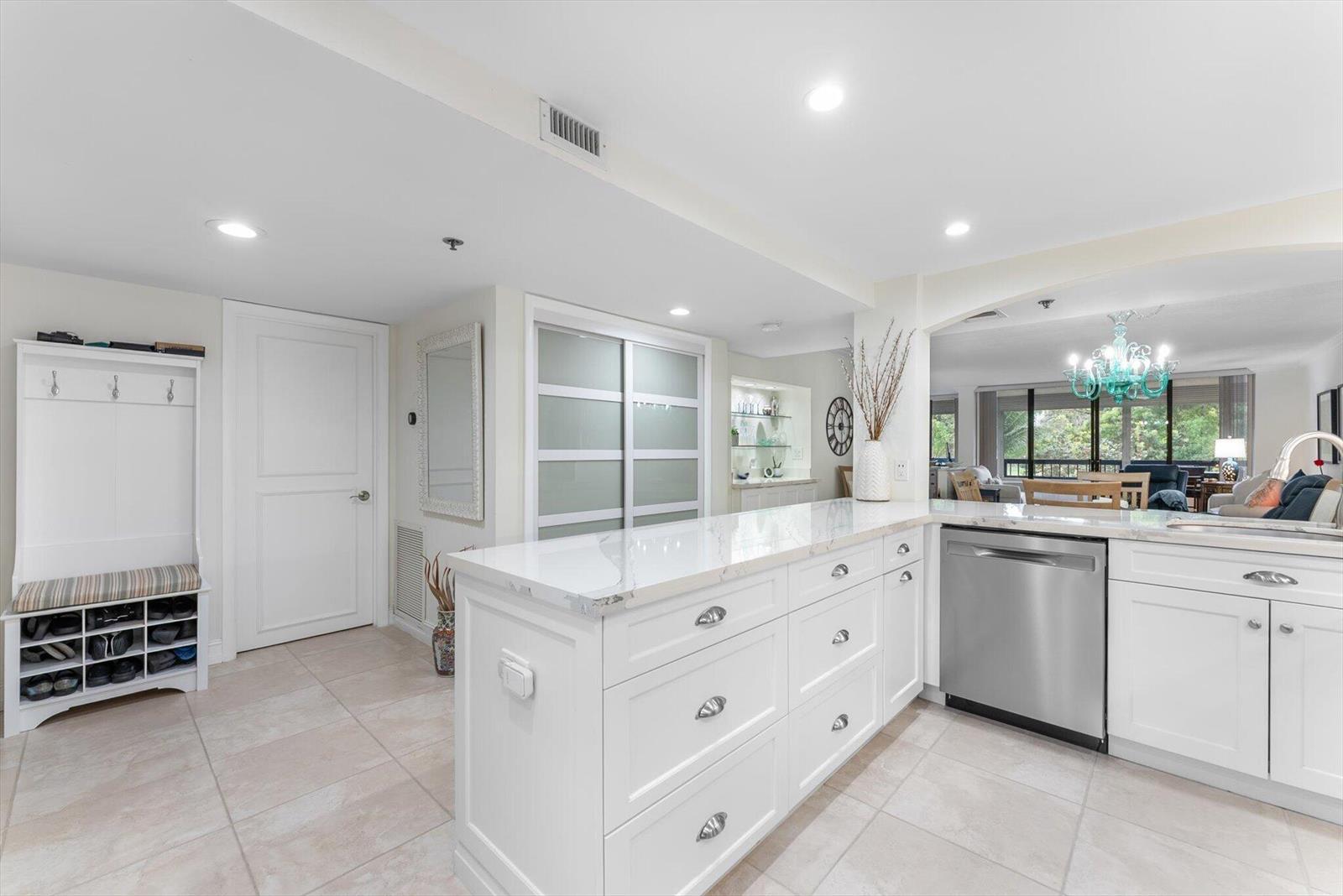 A white kitchen features a marble-topped island, stainless steel dishwasher, and adjacent entryway storage — 6420 Boca Del Mar Drive # 201, Boca Raton FL 33433, BOCA RATON, FL