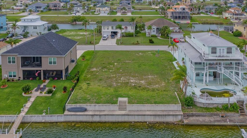 An aerial view shows a vacant waterfront lot situated between two multi-story residential houses — 3471 AMBERJACK DRIVE, HERNANDO BEACH, FL