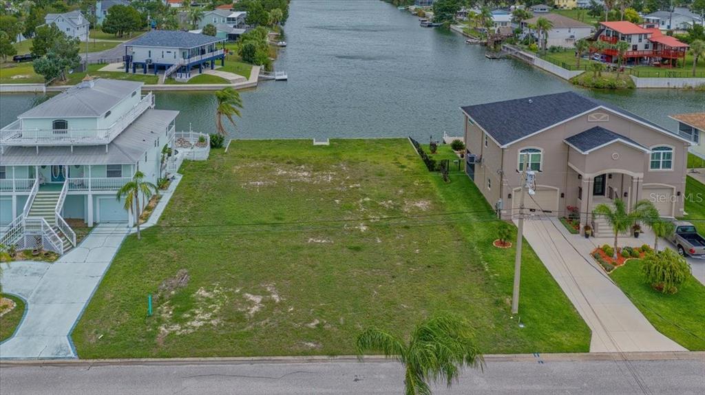 An empty residential lot sits between two houses along a canal — 3471 AMBERJACK DRIVE, HERNANDO BEACH, FL