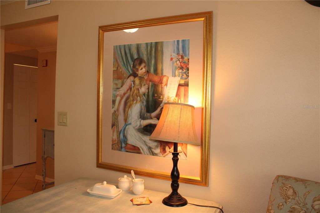 A table with a lamp and a framed print of two girls sits indoors — 2725 TERRA CEIA BAY BOULEVARD UNIT 203, PALMETTO, FL