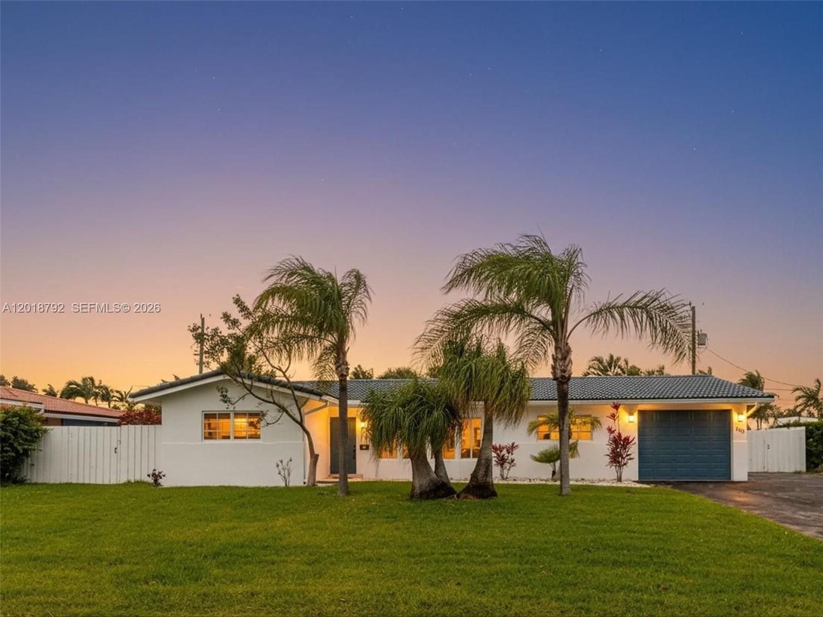 A single-story white house with a blue garage door and palm trees in the yard — 4211 NE 27th Ave, Lighthouse Point FL 33064, LIGHTHOUSE POINT, FL