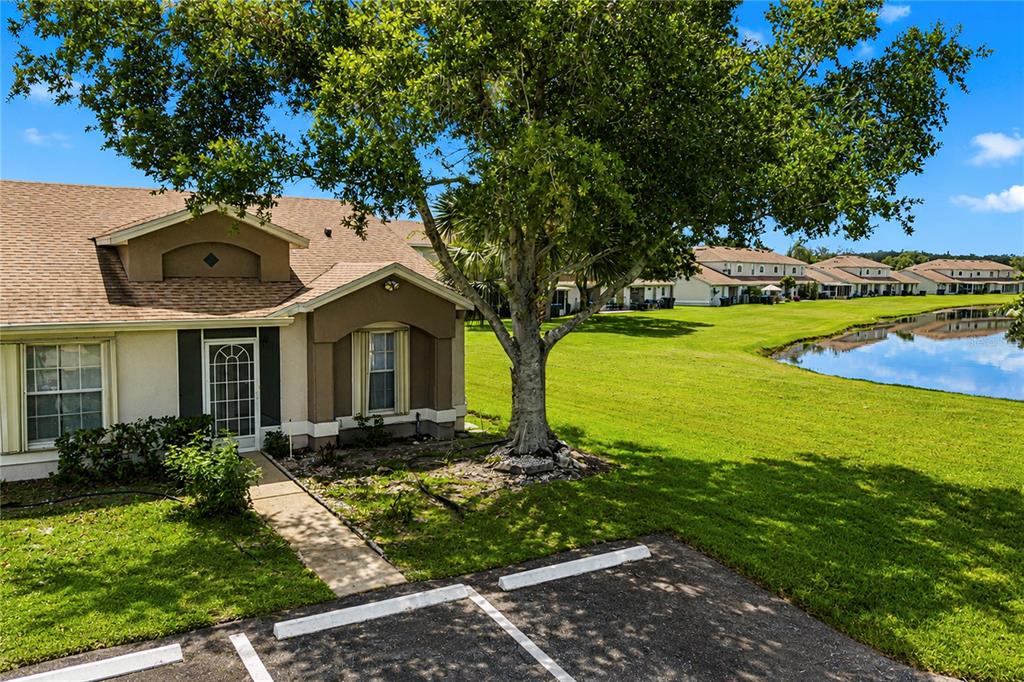 A single-story residential building with a parking space and a tree overlooking a pond — 14431 ISLAND COVE DRIVE, ORLANDO, FL