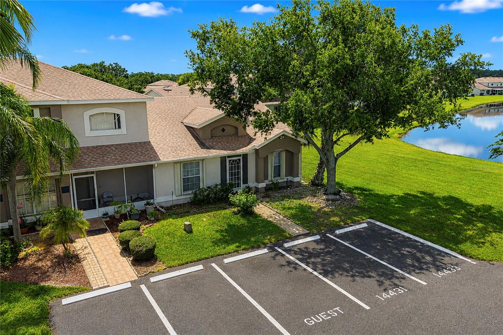 An exterior view of a two-story townhouse with a screened porch and adjacent parking spaces — 14431 ISLAND COVE DRIVE, ORLANDO, FL