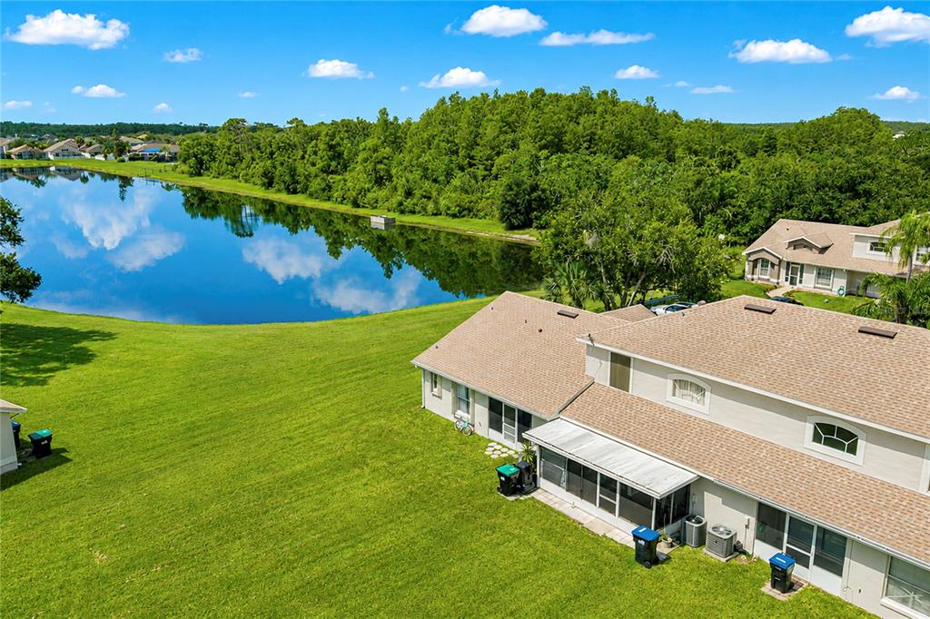 An aerial view shows a two-story house with a screened patio next to a lake — 14431 ISLAND COVE DRIVE, ORLANDO, FL