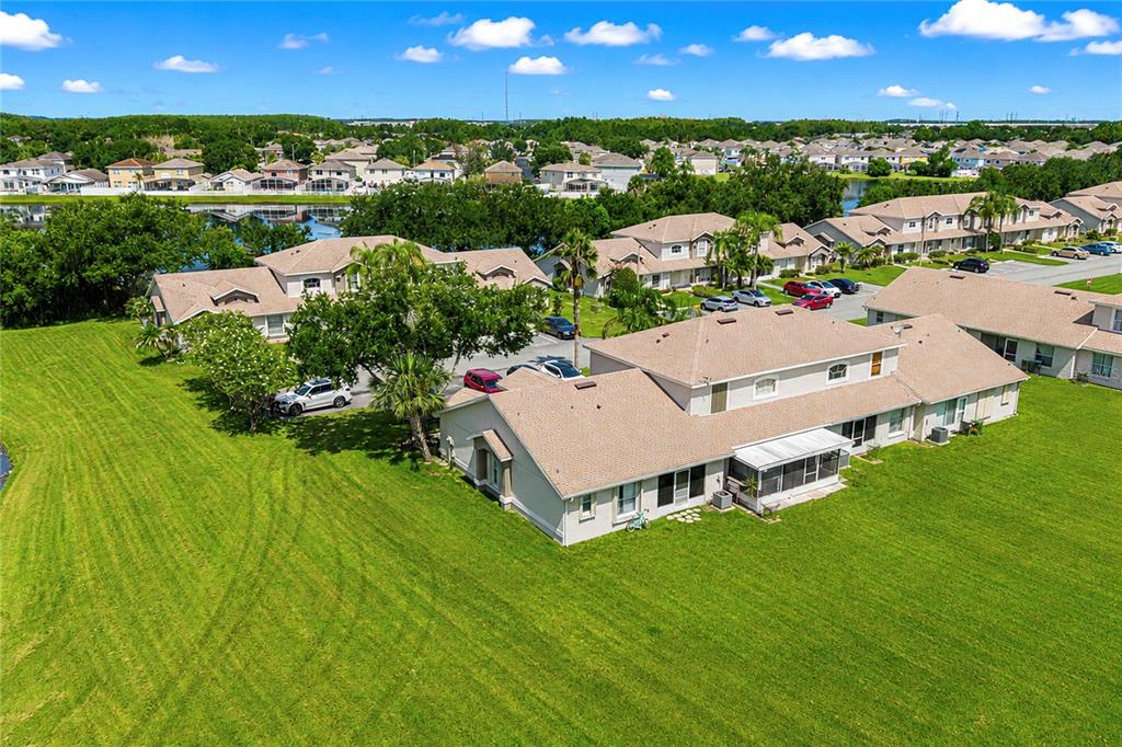 An aerial view shows a multi-unit residential building with a large lawn and pond — 14431 ISLAND COVE DRIVE, ORLANDO, FL