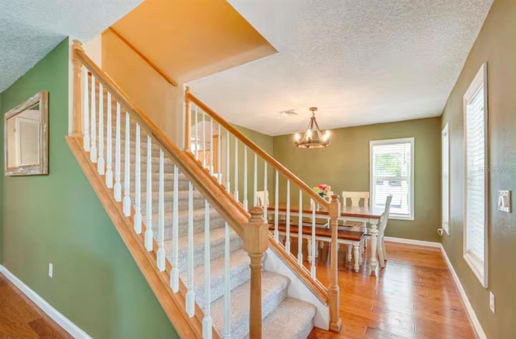 A carpeted staircase with wooden railings leads to an upper level near a dining area — 11895 N BEARL TERRACE, DUNNELLON, FL