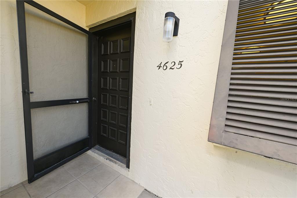 A dark brown front door with a screen door and house number 4625 — 4625 LONGWATER CHASE UNIT 113, SARASOTA, FL