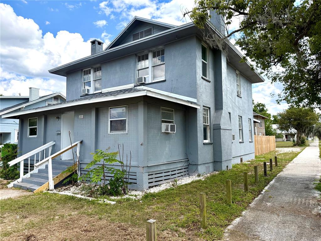 A two-story gray house with a front porch, white railings, and a sidewalk nearby — 204 AVENUE D NE, WINTER HAVEN, FL