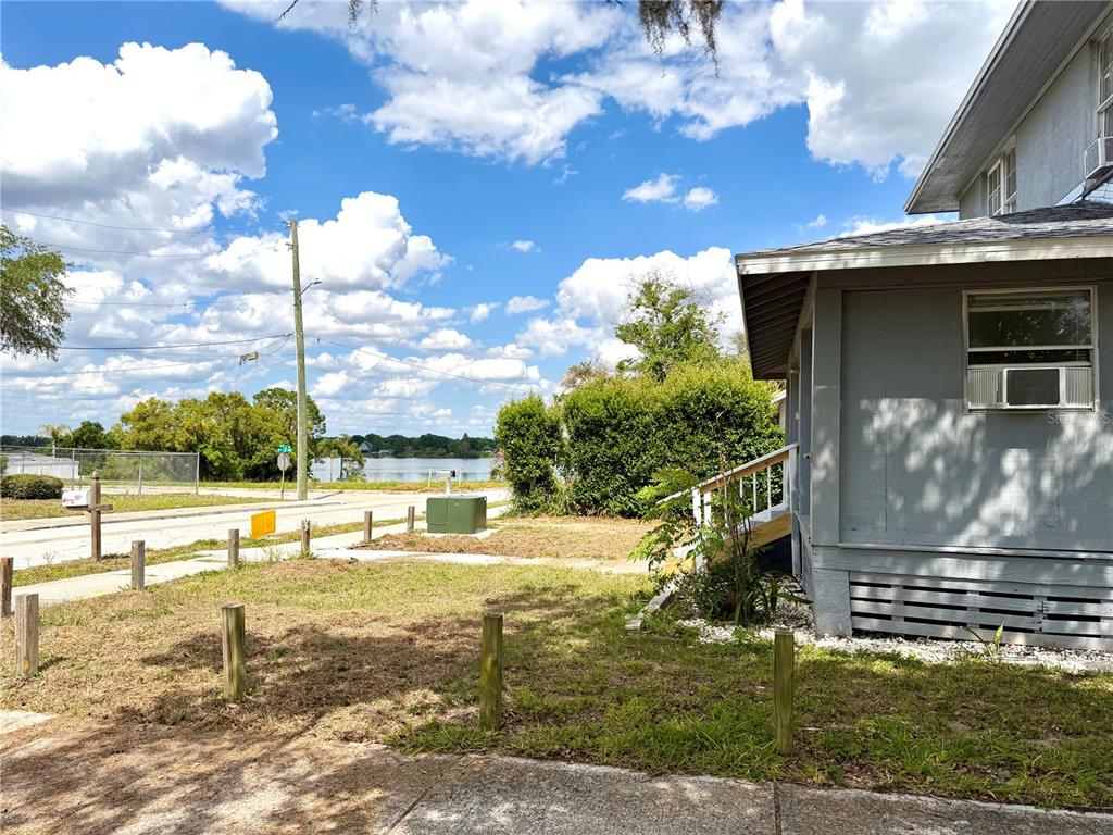 A view of a house exterior, a grassy yard, and a lake in the distance — 204 AVENUE D NE, WINTER HAVEN, FL
