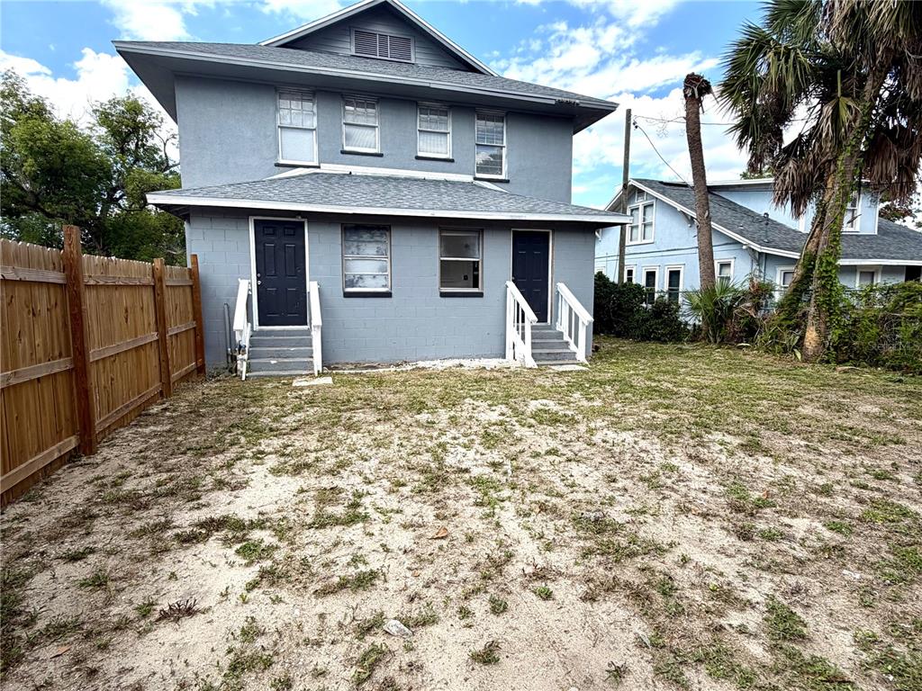The rear exterior of a two-story gray house features two entry doors and a yard — 204 AVENUE D NE, WINTER HAVEN, FL