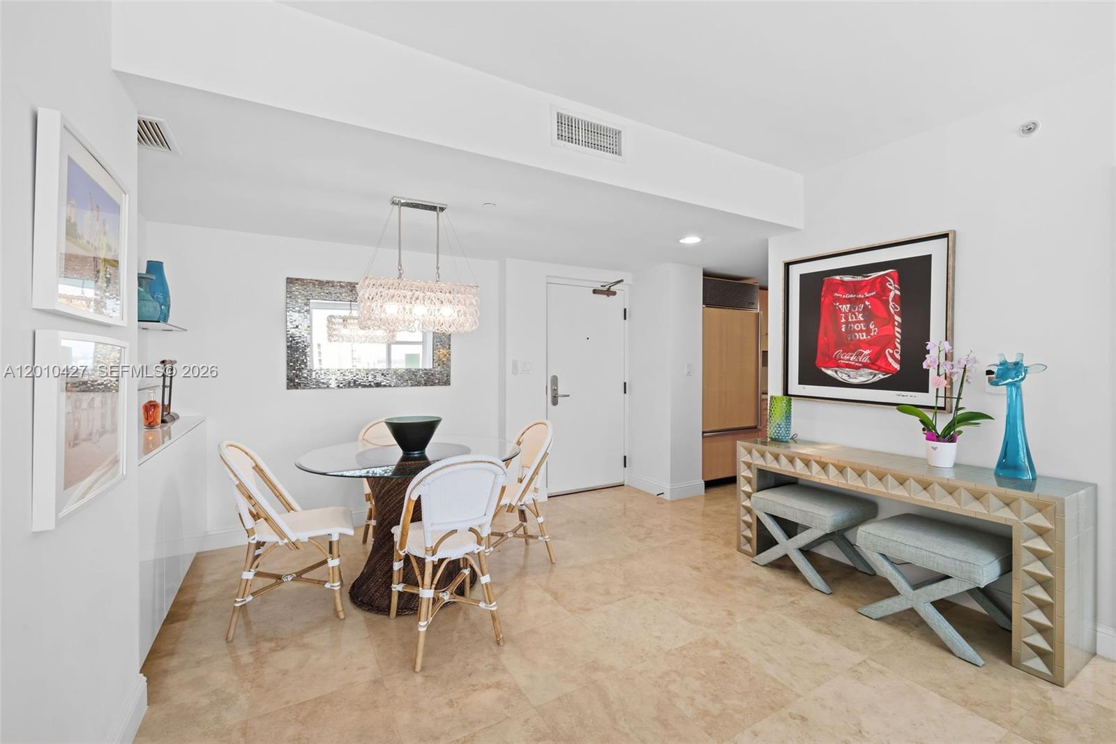 A dining area features a glass-topped table, rattan chairs, and a console table with stools — 6801 Collins Ave # 1215, Miami Beach FL 33141, MIAMI BEACH, FL