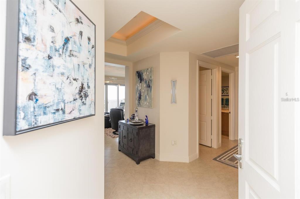 An entryway leads into a tiled hallway with abstract art and a view of a living area — 85 AVENUE DE LA MER UNIT 805, PALM COAST, FL