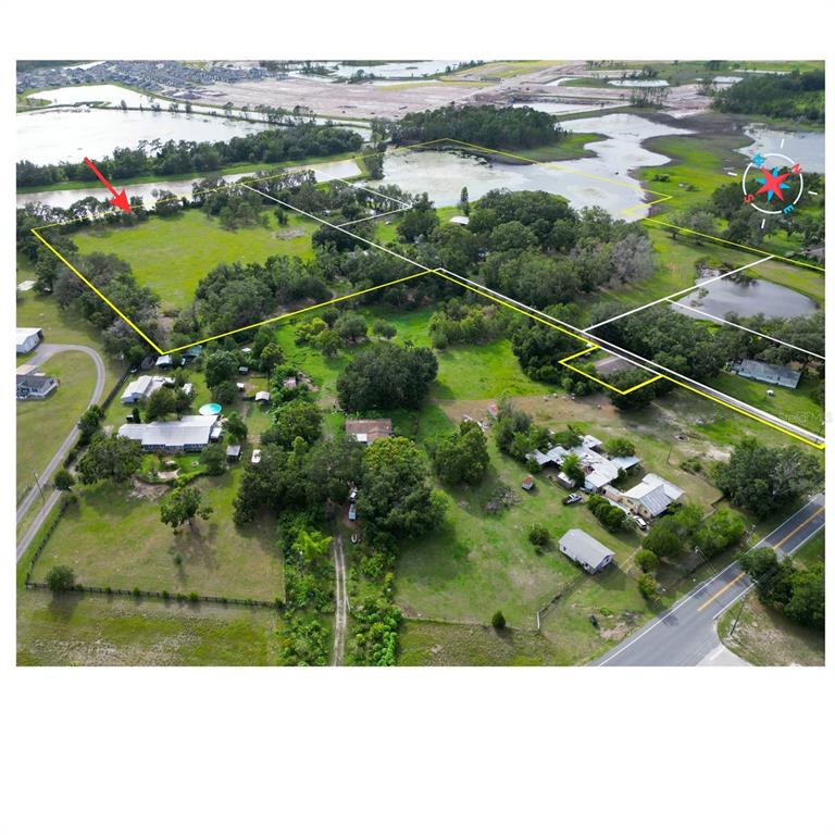 An aerial view shows multiple rural properties with houses, green pastures, and surrounding wetlands — 22838 BUNGALOW LANE, LAND O LAKES, FL