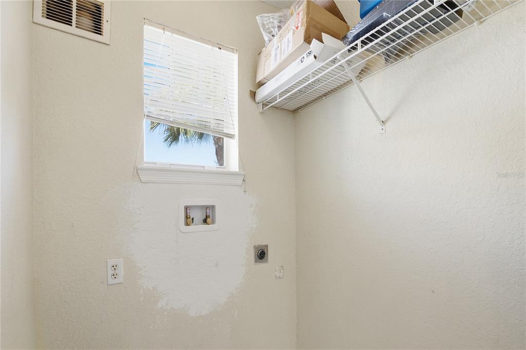 A laundry room features a window, a wire shelf, and wall-mounted utility connections — 2207 ANTIGUA PLACE UNIT 738, KISSIMMEE, FL