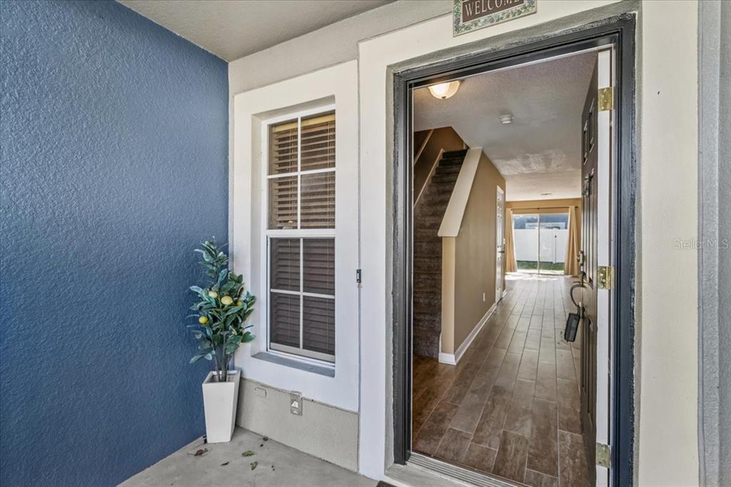 An open front door reveals a tiled entryway with a staircase leading to the second floor — 13054 LEXINGTON SUMMIT STREET, ORLANDO, FL
