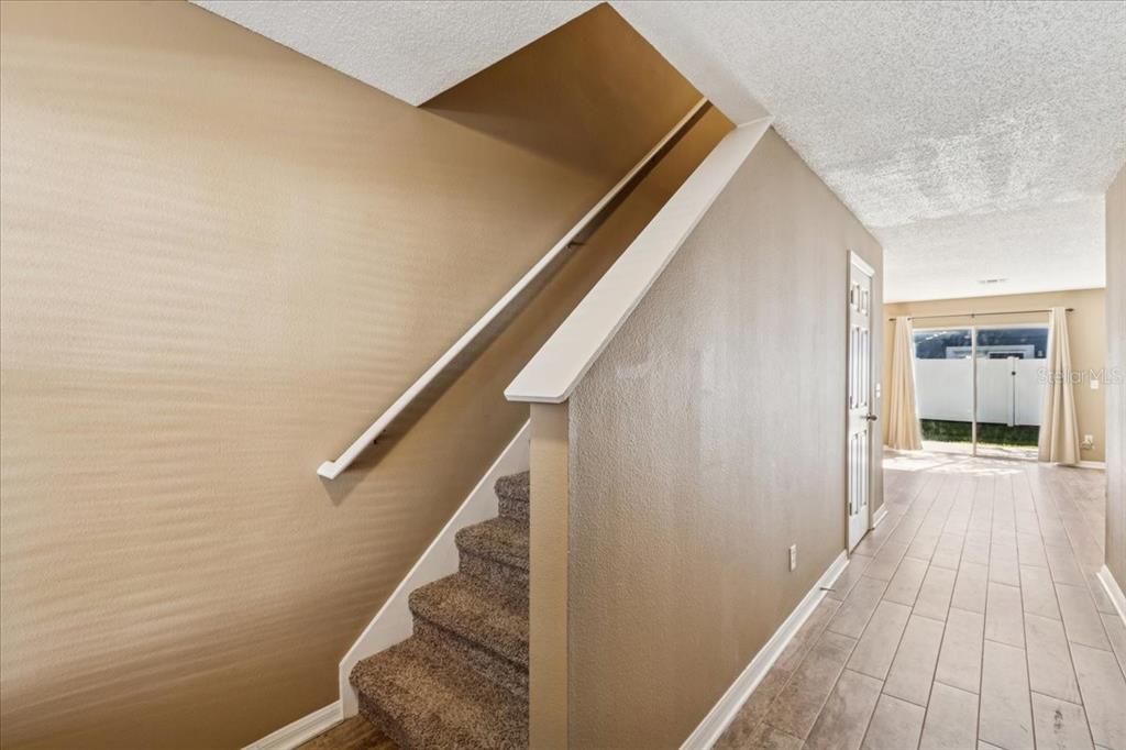 A staircase with carpeted steps and a white railing sits beside a tiled hallway — 13054 LEXINGTON SUMMIT STREET, ORLANDO, FL