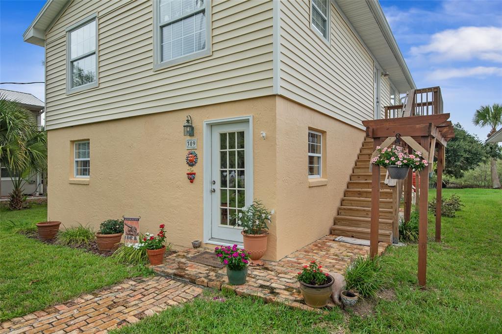 A two-story house with beige siding, a stucco ground floor, and an exterior wooden staircase — 309 CYPRESS STREET, FLAGLER BEACH, FL