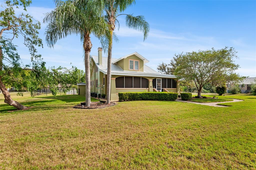 A green house with a metal roof and a screened porch sits on a lawn — 501 MAIN STREET, LAKE HAMILTON, FL