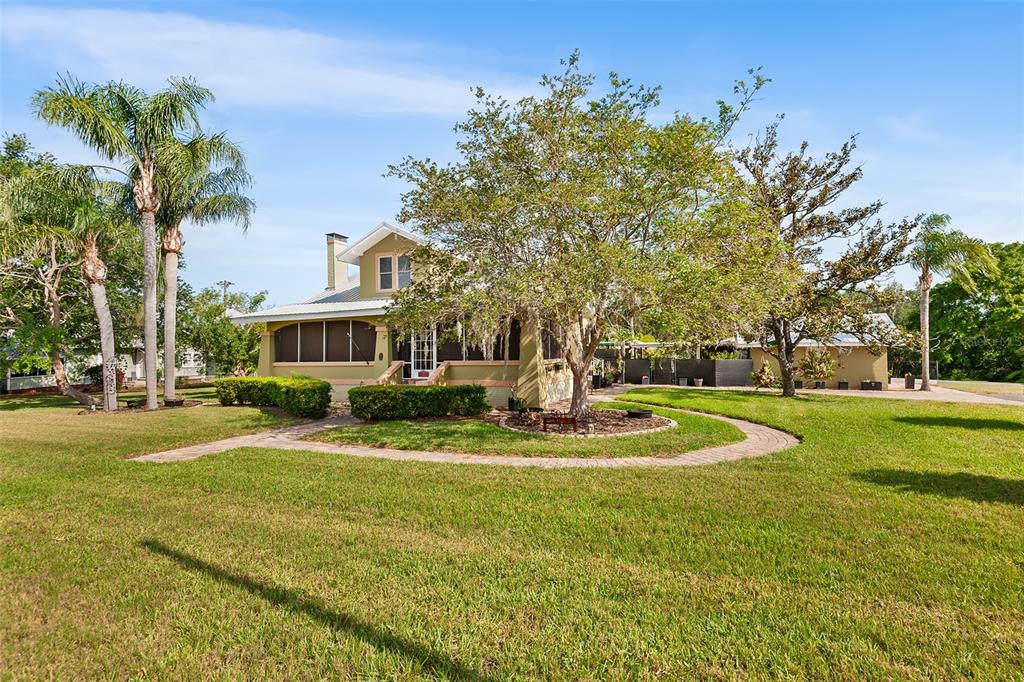 A light green house with a wraparound porch sits on a grassy lot with trees — 501 MAIN STREET, LAKE HAMILTON, FL