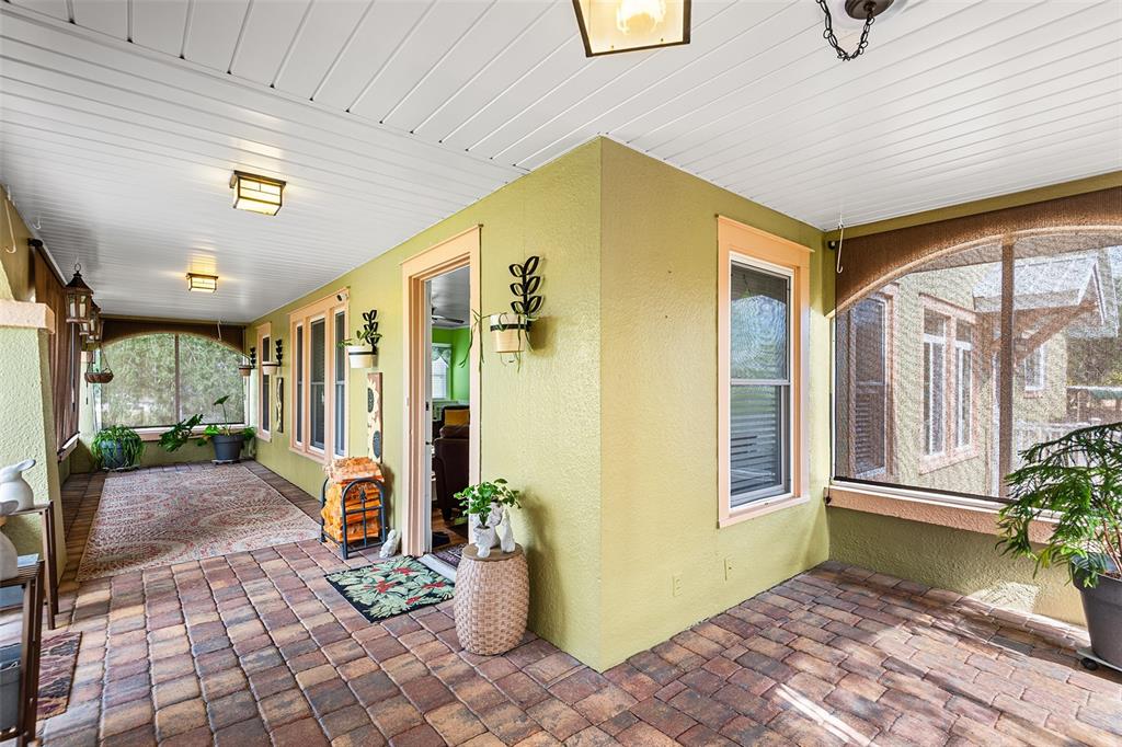 A covered patio features paver flooring, light green walls, and screened-in sections — 501 MAIN STREET, LAKE HAMILTON, FL