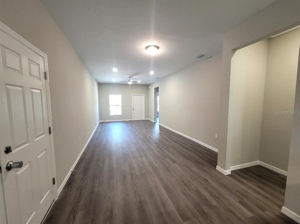 An interior view of a long, open-concept room with light gray walls and wood-look flooring — 5025 FINDERS COURT, TAMPA, FL