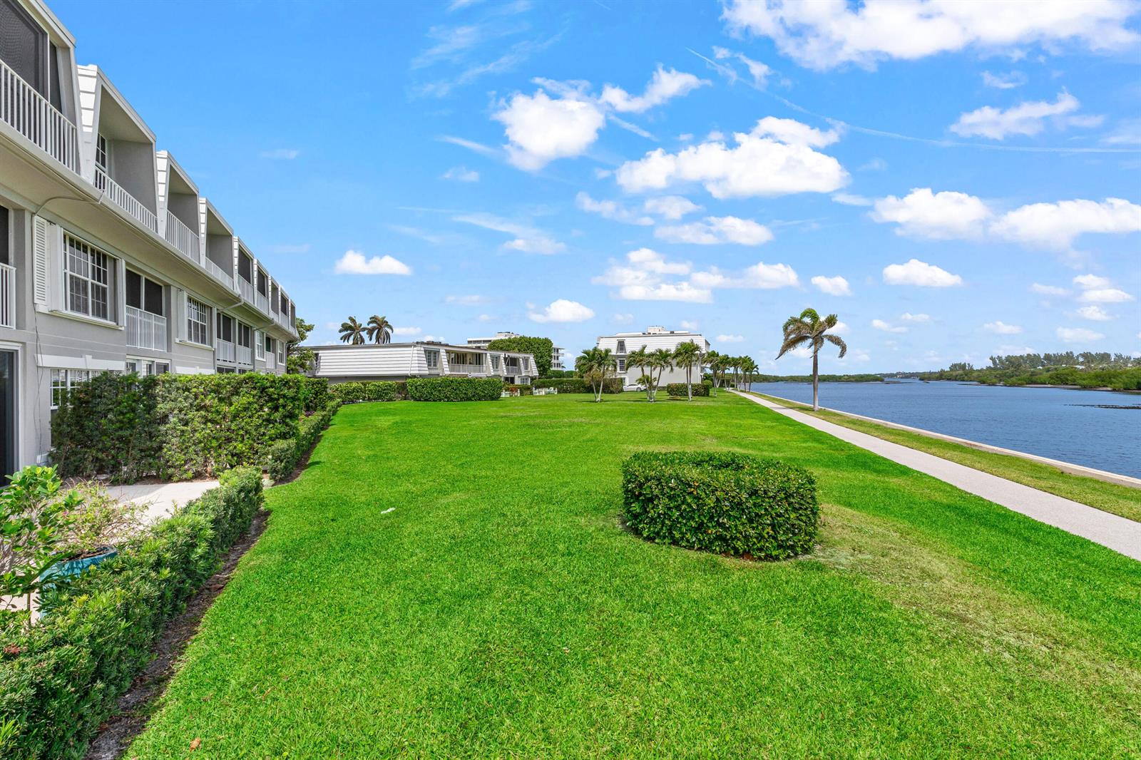 A multi-story apartment building overlooks a large green lawn, a sidewalk, and a waterway — 2185 Ibis Isle Road # 1, Palm Beach FL 33480, PALM BEACH, FL