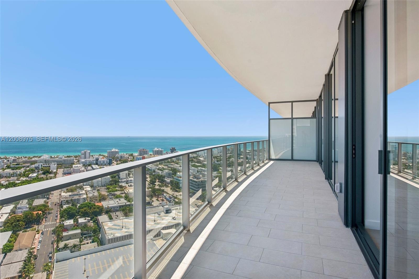 A high-rise balcony features glass railings, light-colored tile flooring, and panoramic ocean and city views — 500 Alton Rd. # 3004, Miami Beach FL 33139, MIAMI BEACH, FL