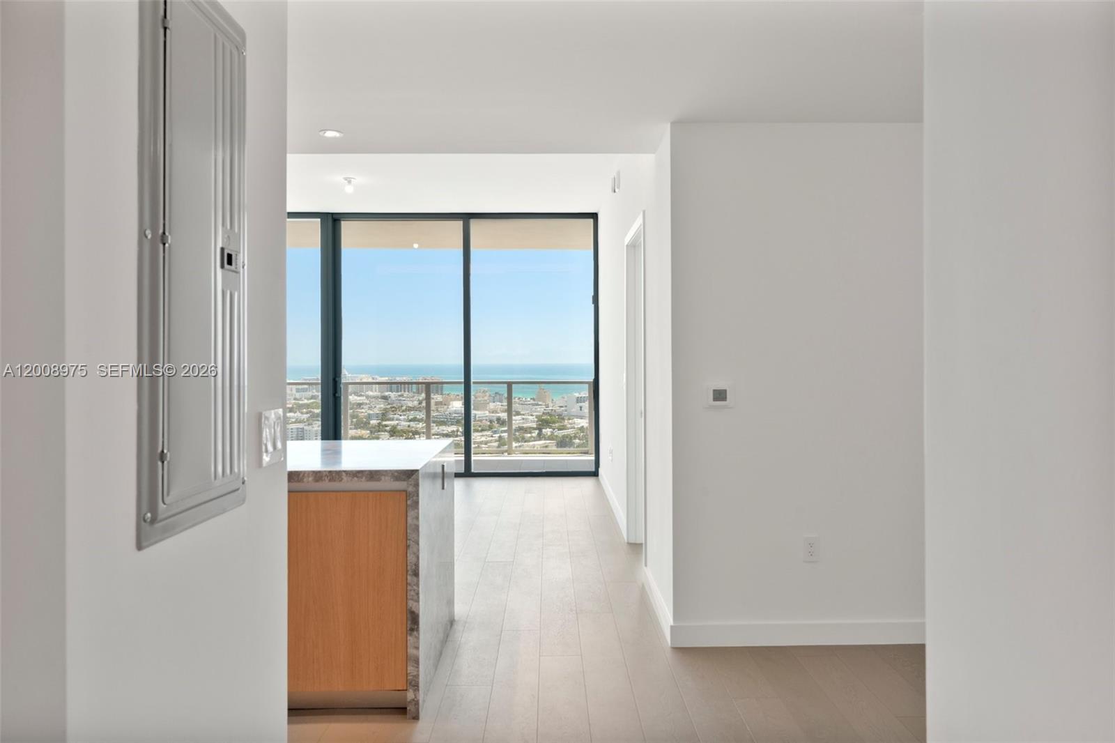 A modern kitchen with light wood cabinets and marble countertops overlooks a coastal city view — 500 Alton Rd. # 3004, Miami Beach FL 33139, MIAMI BEACH, FL